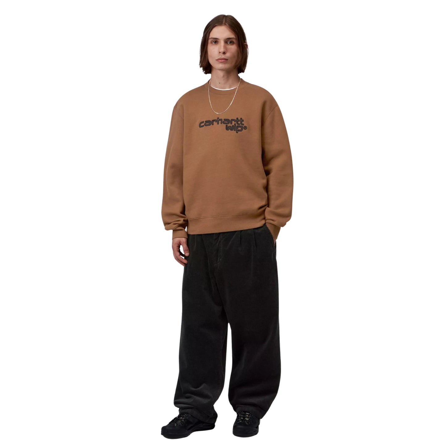 Camisola Carhartt WIP Wireless Sweat em Hamilton Brown / Black — modelo masculino de frente, corpo inteiro, cabelo comprido castanho, fio de ouro fino ao pescoço, anel dourado no dedo, bordado "carhartt wip®" visível ao peito, calças wide-leg bombazine preto, sapatilhas chunky pretas, malha de algodão escovada castanha Hamilton Brown, fundo branco.