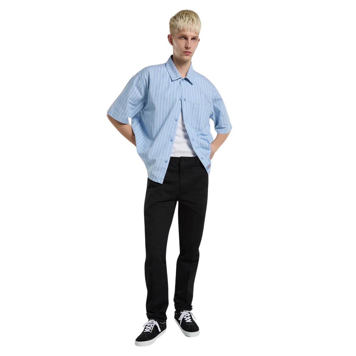 Calças Dickies 247 Slim Work Pant em Preto — modelo de corpo inteiro, calças pretas de corte slim com pinças frontais, camisa azul-clara às riscas e sapatilhas skate pretas, fundo branco.