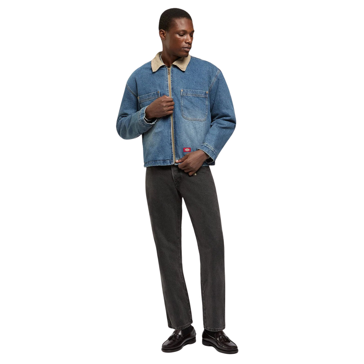 Modelo com calças de ganga Dickies 983 Regular Straight em preto lavado, casaco de ganga azul e sapatos pretos.