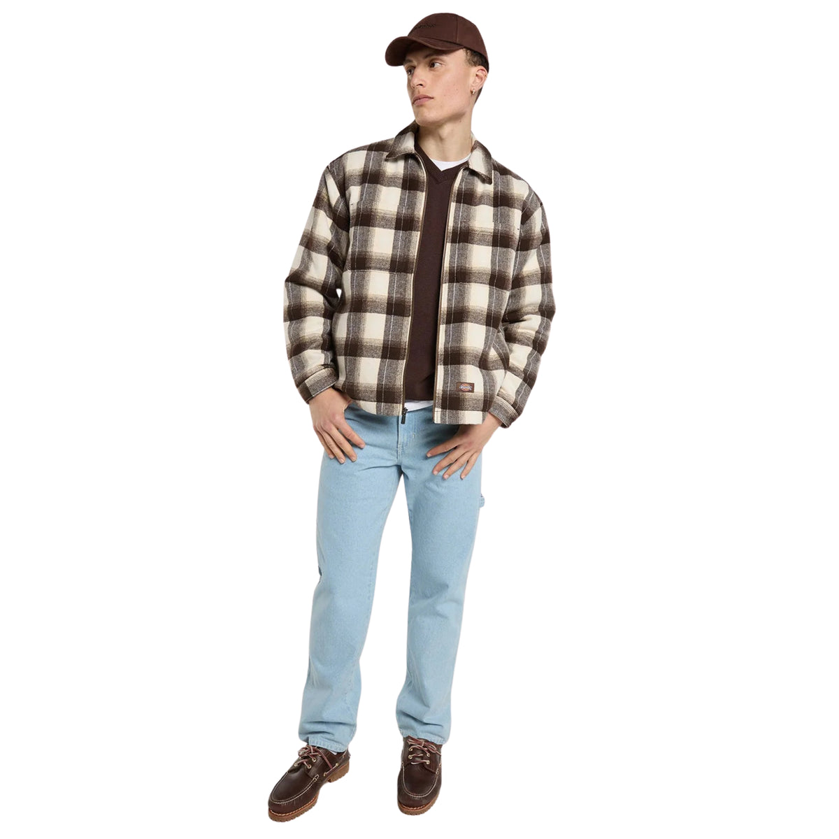 Modelo de corpo inteiro com sobrecamisa Dickies Florence Timber Brown aberta, calças de ganga clara e boné castanho.