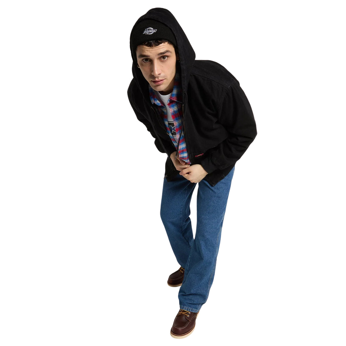 Modelo de corpo inteiro com casaco Dickies Hilham preto aberto, capuz colocado sobre um gorro e calças de ganga azuis.