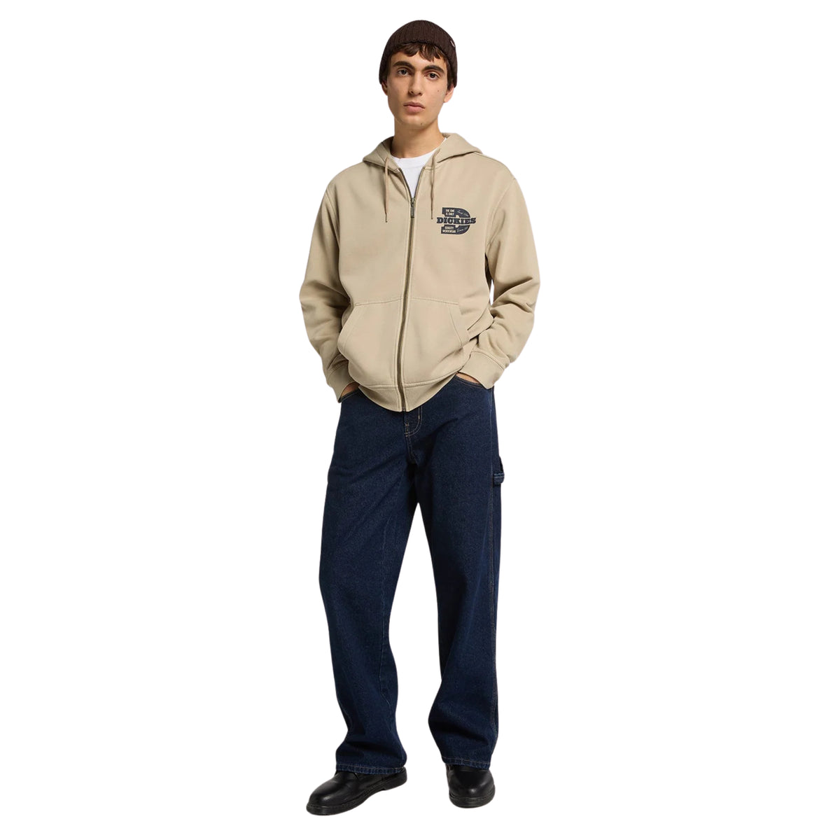 Modelo de corpo inteiro com sweat Dickies Minden Desert Sand, calças de ganga escura e gorro castanho.