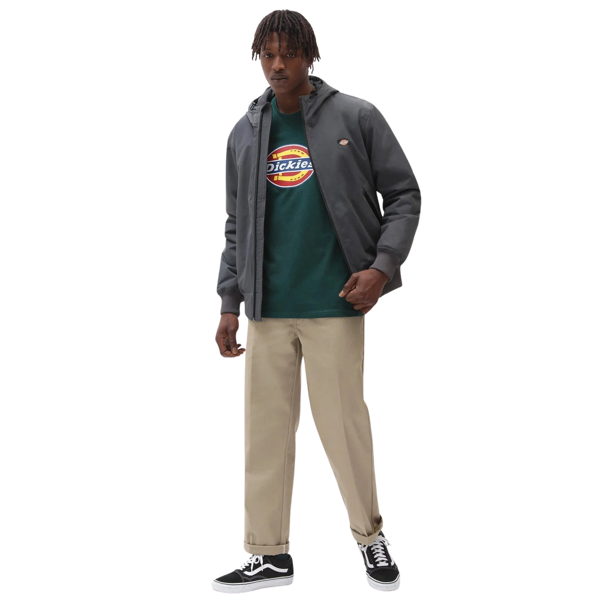 Modelo de corpo inteiro com casaco Dickies New Sarpy em Charcoal aberto, t-shirt verde, calças bege e sapatilhas pretas e brancas.