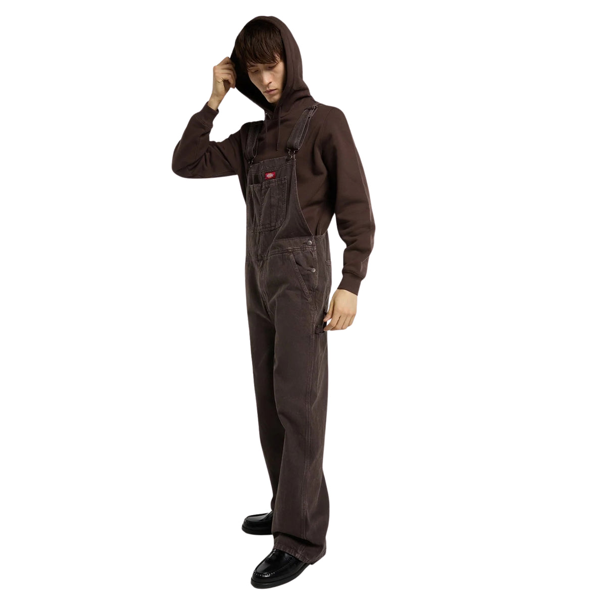 Sweat com carapuço Dickies Oakport em Chocolate Brown — modelo de corpo inteiro de perfil com carapuço erguido, vestindo jardineiras Dickies a condizer.