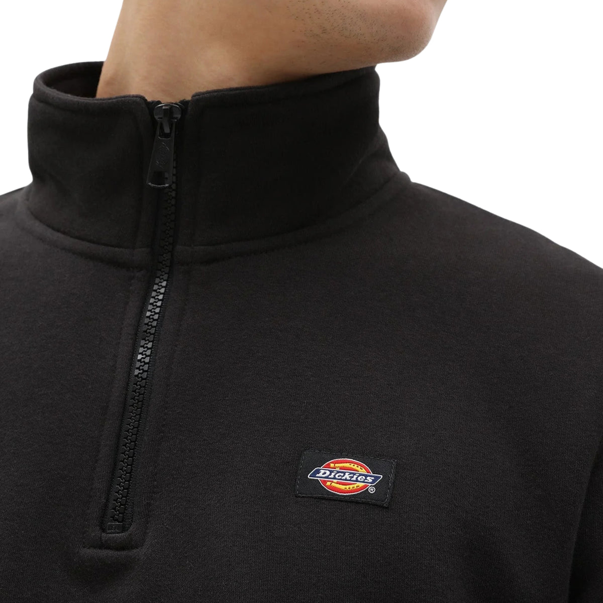 Pormenor da sweat Dickies Oakport preta, mostrando a gola alta, o fecho de correr curto e a etiqueta Dickies tecida no peito à esquerda.
