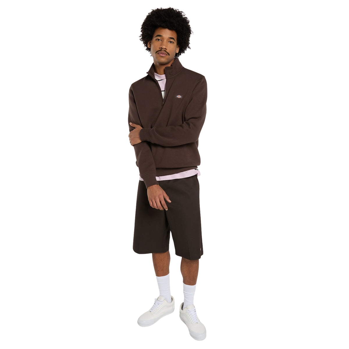 Sweat Dickies Oakport Quarter Zip em Chocolate Brown, vista de corpo inteiro no modelo, com meio fecho aberto sobre uma t-shirt clara, calções escuros e sapatilhas brancas.