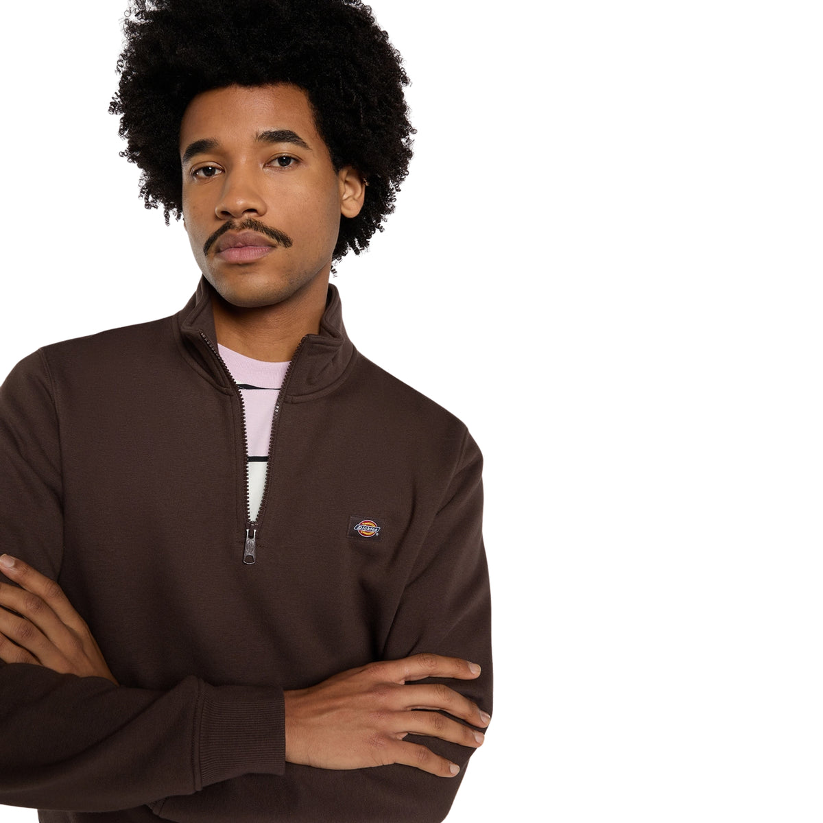 Sweat Dickies Oakport Quarter Zip em Chocolate Brown, close-up da parte superior no modelo de braços cruzados, mostrando a gola alta, o meio fecho aberto e a etiqueta Dickies no peito esquerdo.