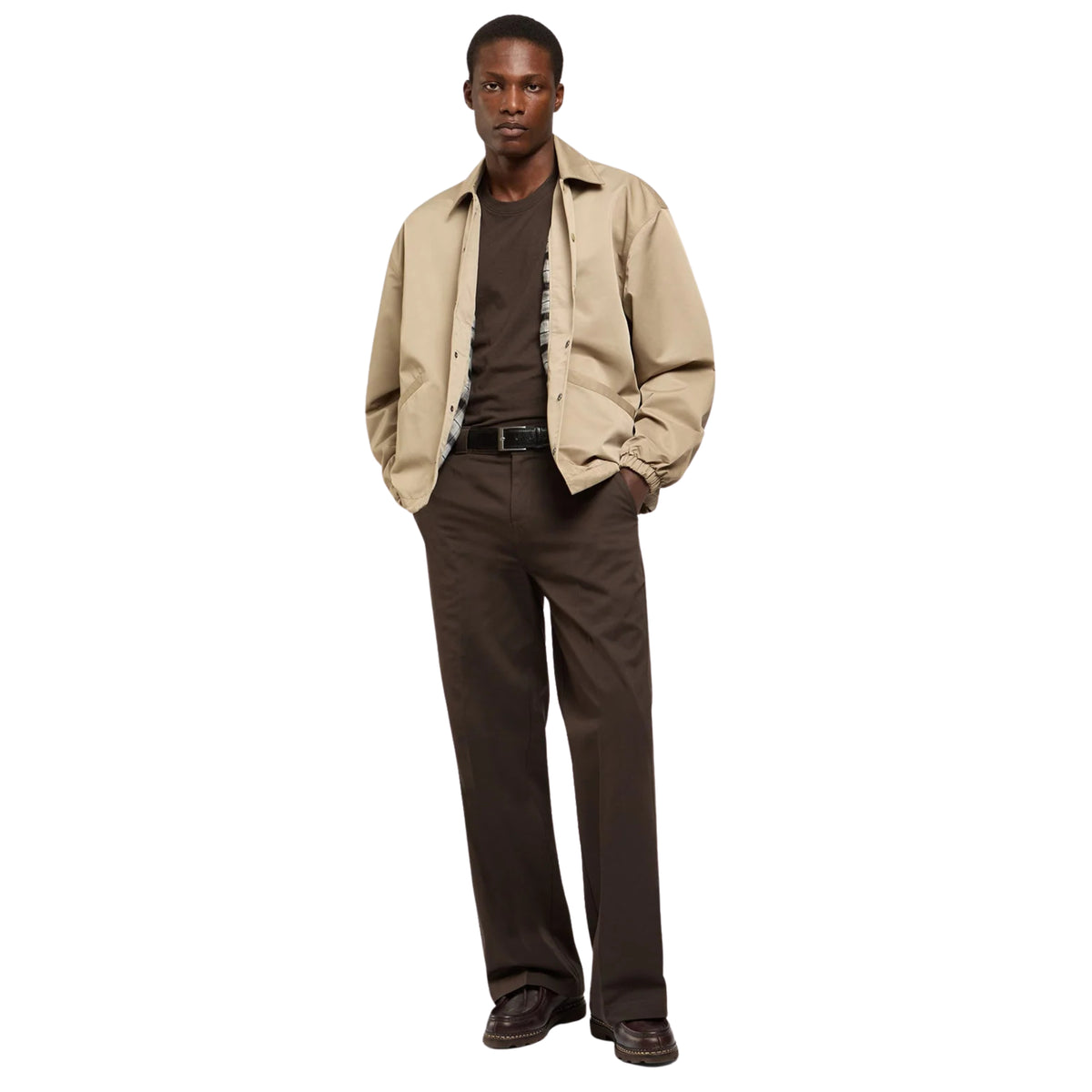 Modelo de corpo inteiro com casaco Dickies Parks Khaki aberto sobre t-shirt castanha, com calças e sapatos castanhos.