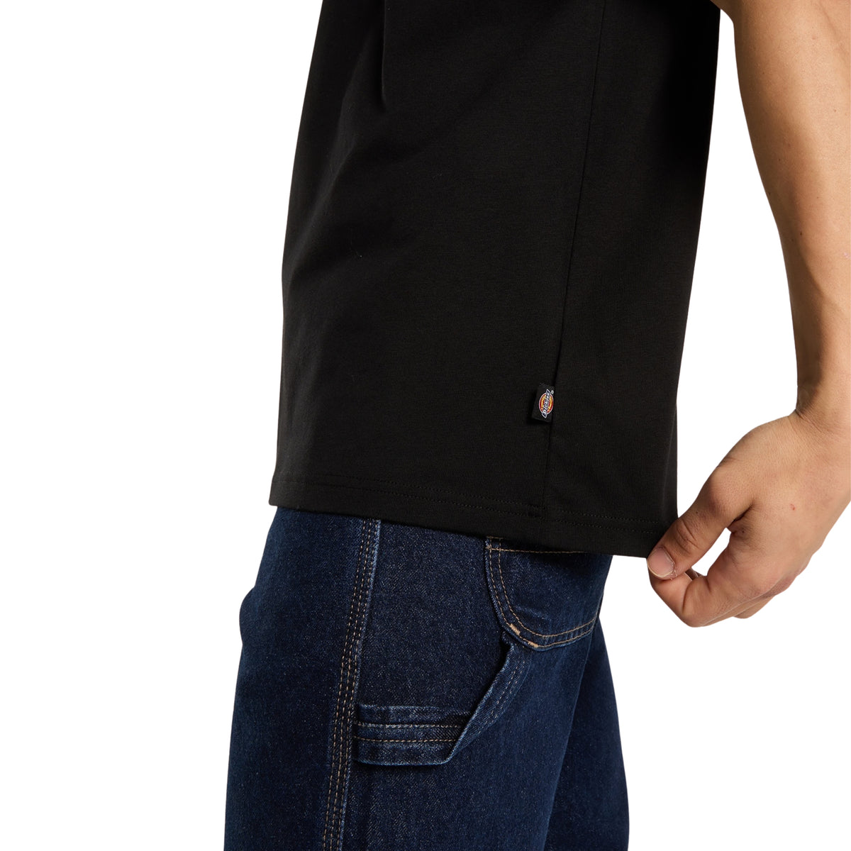 Pormenor da bainha e da costura lateral da t-shirt Dickies Racing preta, com pequena etiqueta Dickies junto à base.
