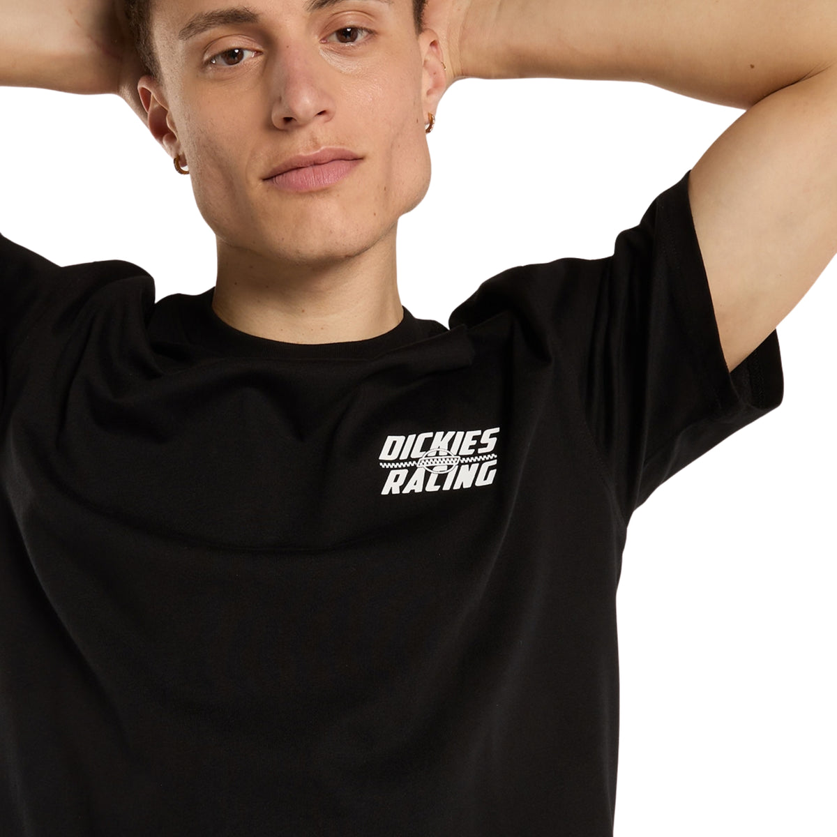 Pormenor frontal da t-shirt Dickies Racing preta em modelo com braços levantados, mostrando a gola redonda e o pequeno gráfico branco no peito.