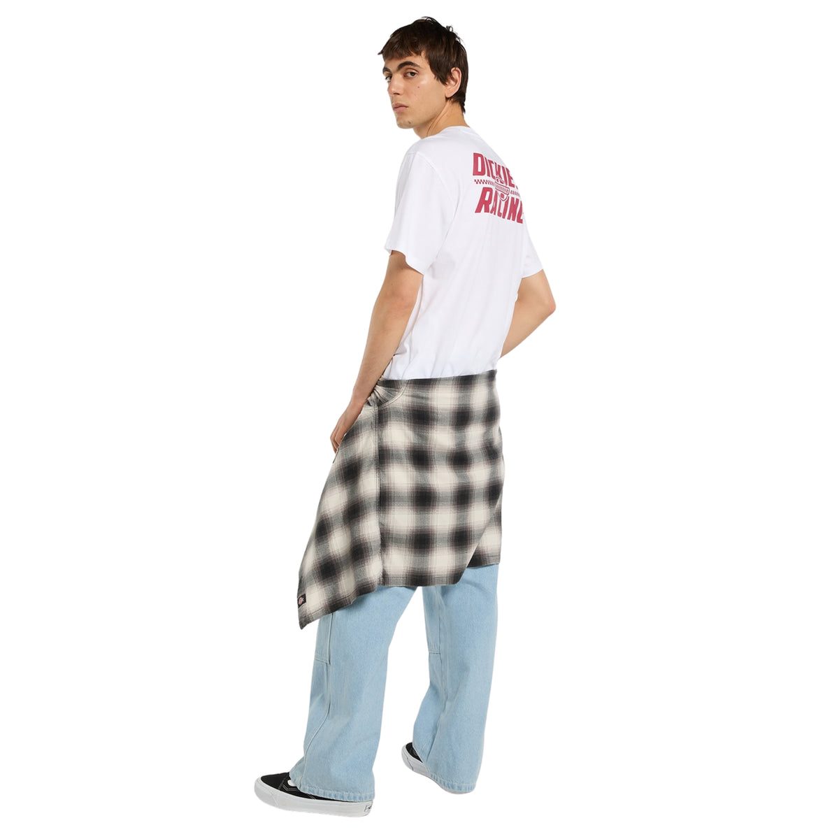 Modelo de corpo inteiro de costas a três quartos com t-shirt Dickies Racing branca, gráfico vermelho nas costas e camisa aos quadrados atada à cintura.
