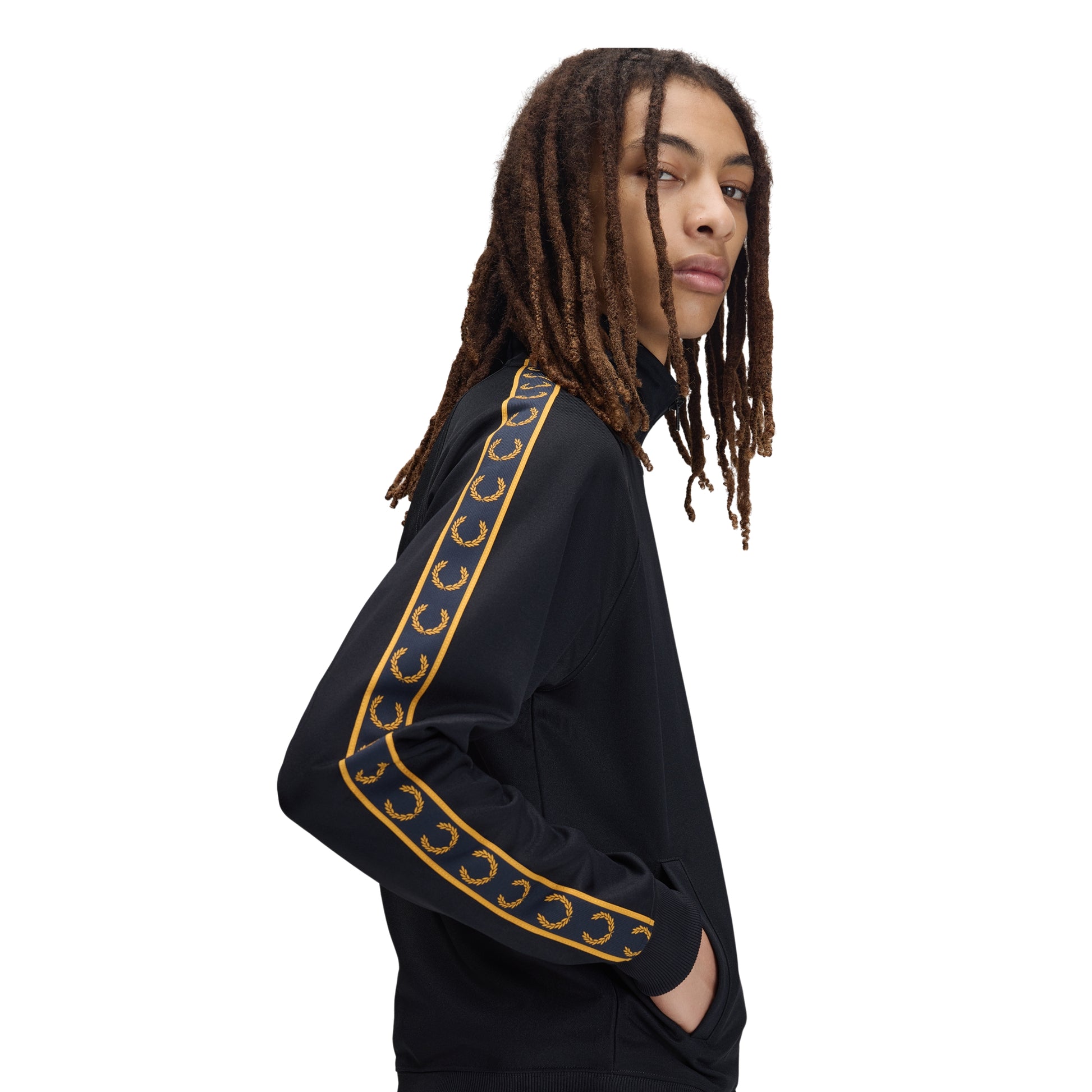 Track jacket Fred Perry Contrast Tape Track Jacket em Navy — vista lateral com modelo, meio corpo, detalhe da fita contrastante dourada com Laurel Wreaths na manga, mão no bolso.
