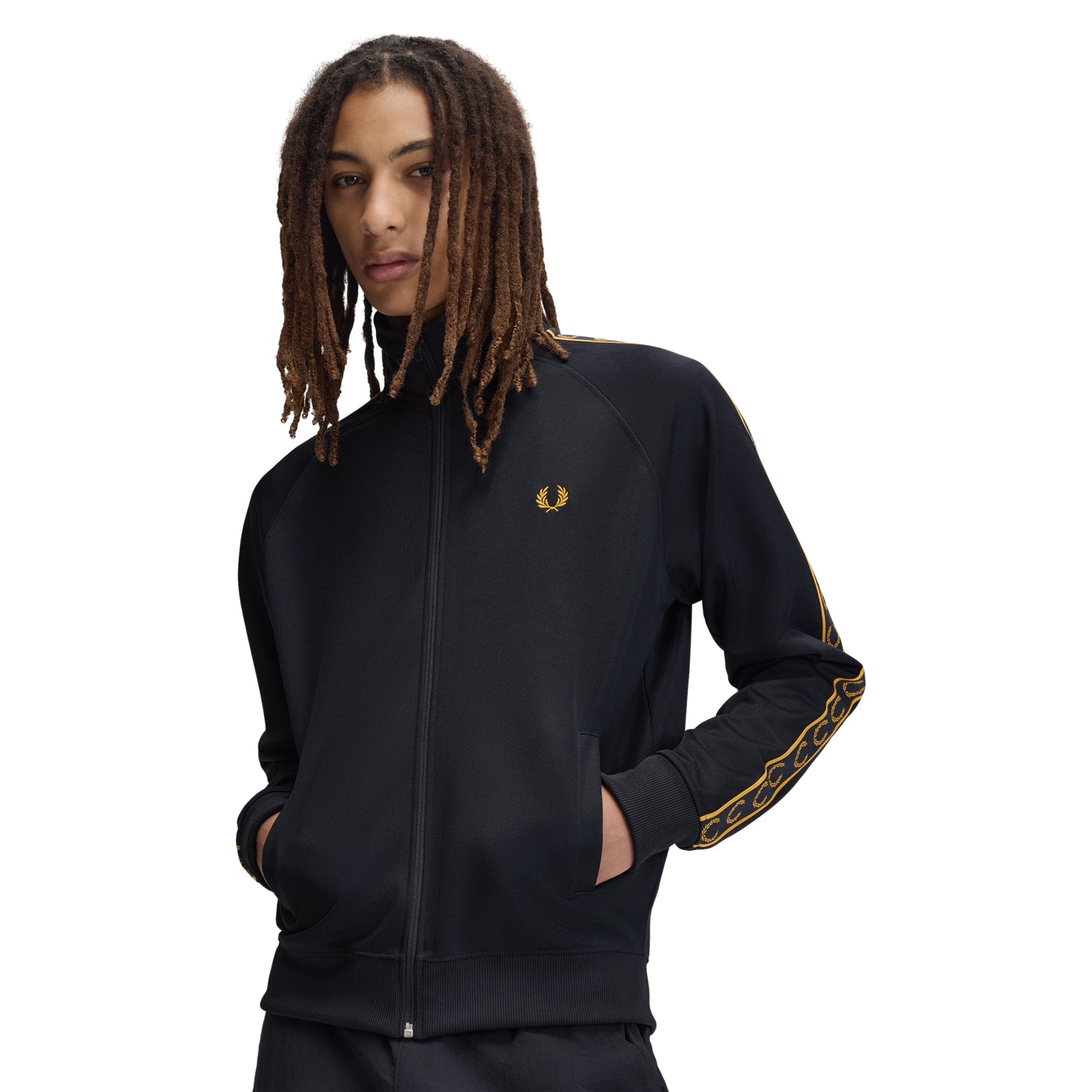 Track jacket Fred Perry Contrast Tape Track Jacket em Navy — vista frontal com modelo, meio corpo, fecho zip fechado, bordado Laurel Wreath em Golden no peito esquerdo, fita contrastante dourada com Laurel Wreaths nas mangas visível.

