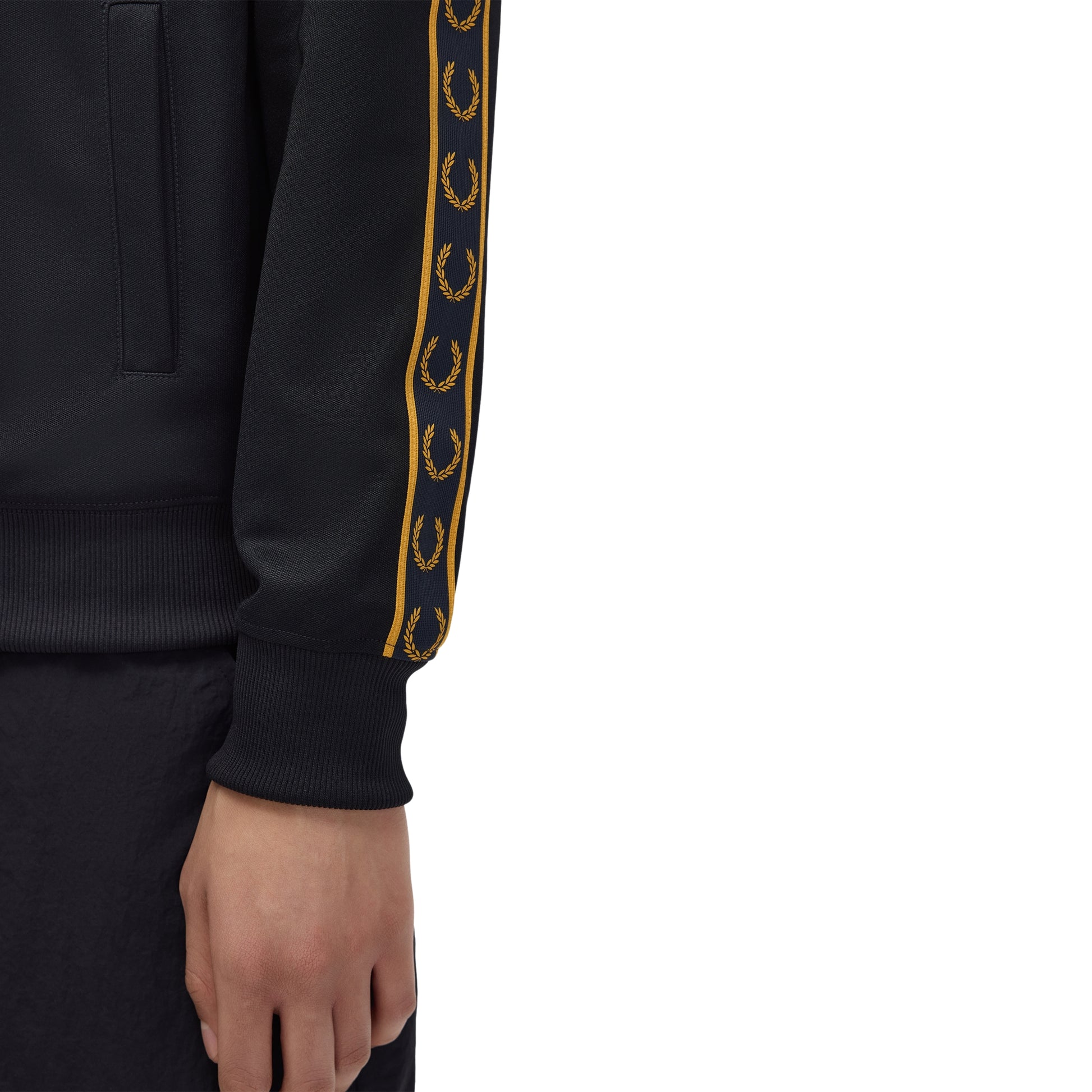 Track jacket Fred Perry Contrast Tape Track Jacket em Navy — detalhe da fita contrastante dourada com Laurel Wreaths repetidos ao longo da manga sobre fundo Navy, textura do tricot visível.