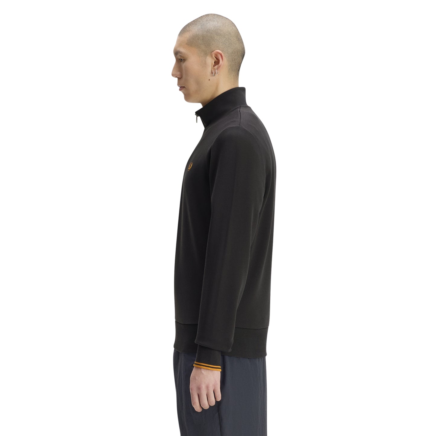 Sweat com meio-fecho Fred Perry Half Zip Sweatshirt em Anchor Grey — vista lateral com modelo, corpo inteiro, perfil do meio-fecho e gola alta visíveis, twin tipping Golden nos punhos, combinado com calças navy.