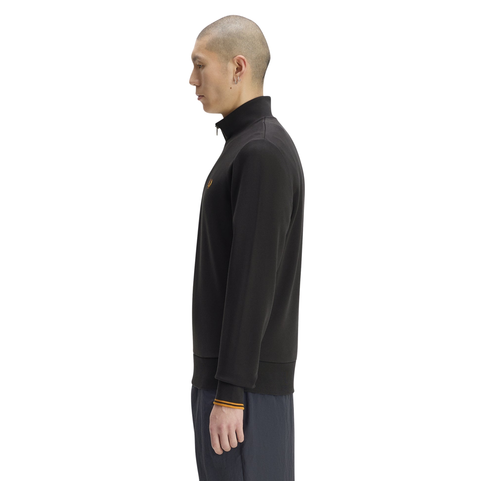 Sweat com meio-fecho Fred Perry Half Zip Sweatshirt em Anchor Grey — vista lateral com modelo, corpo inteiro, perfil do meio-fecho e gola alta visíveis, twin tipping Golden nos punhos, combinado com calças navy.