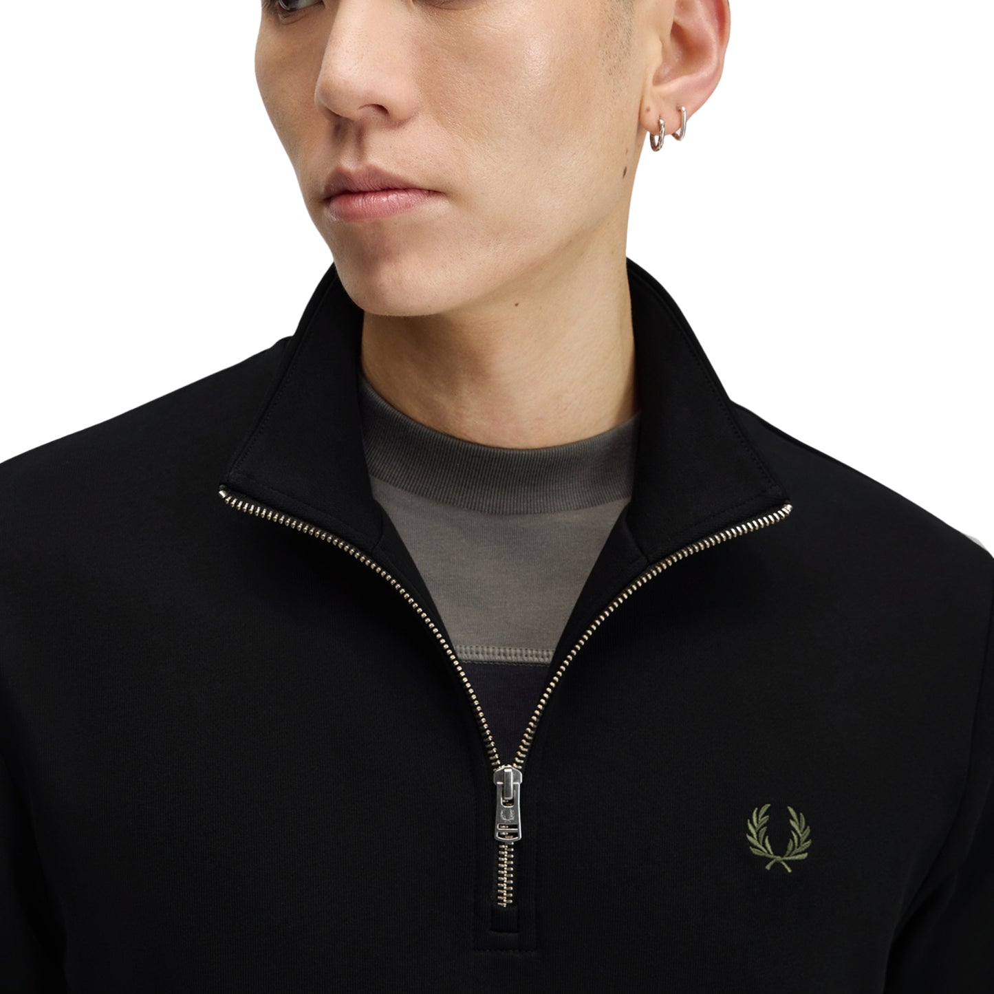 Sweat com meio-fecho Fred Perry Half Zip Sweatshirt em Black — vista frontal com modelo, corpo inteiro, meio-fecho fechado, bordado Laurel Wreath em Laurel Wreath Green e twin tipping nos punhos visíveis, combinado com calças navy Fred Perry.