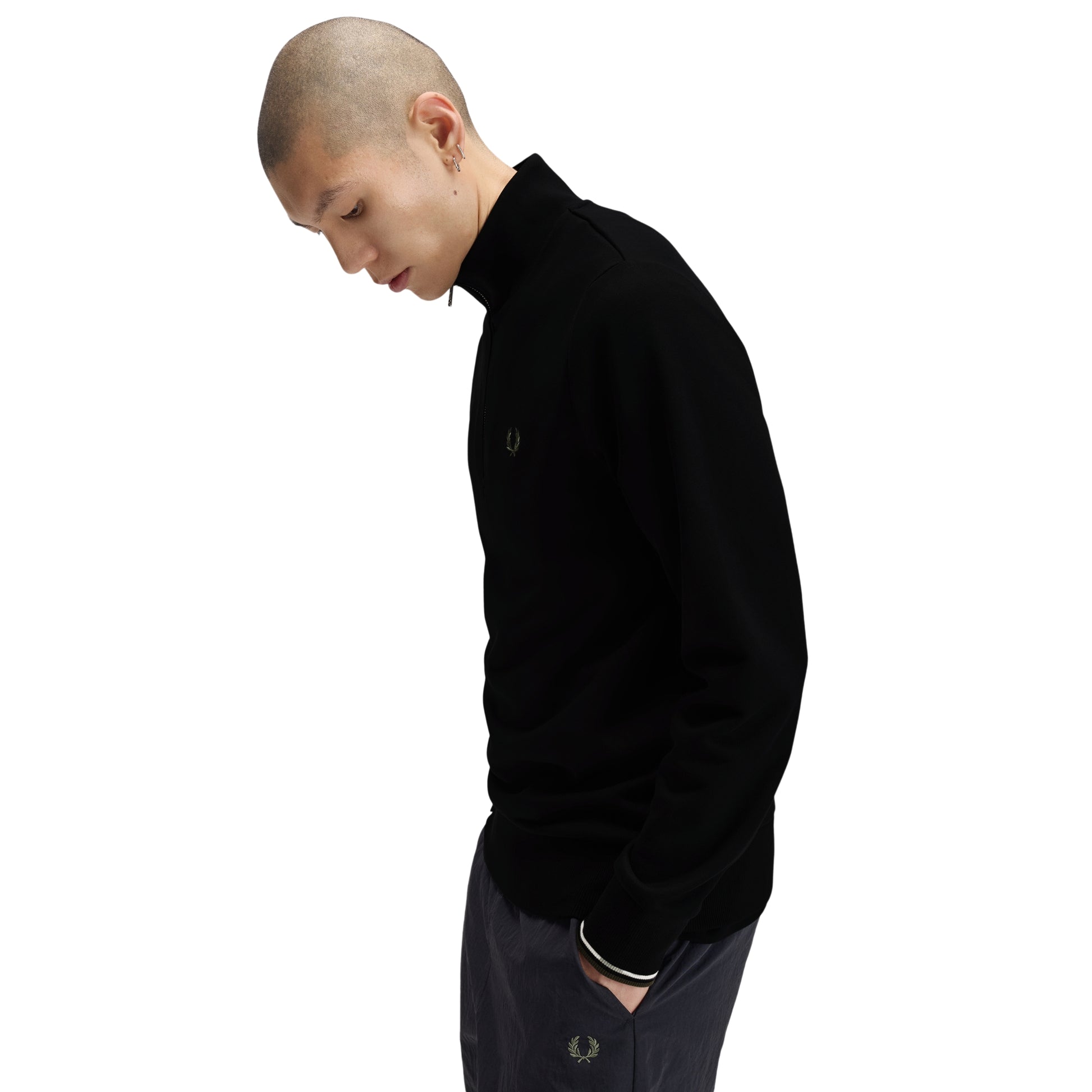 Sweat com meio-fecho Fred Perry Half Zip Sweatshirt em Black — detalhe do punho com twin tipping Ecru/Laurel Wreath Green na proporção 5-4-4, bordado Laurel Wreath em Laurel Wreath Green nas calças navy visível.