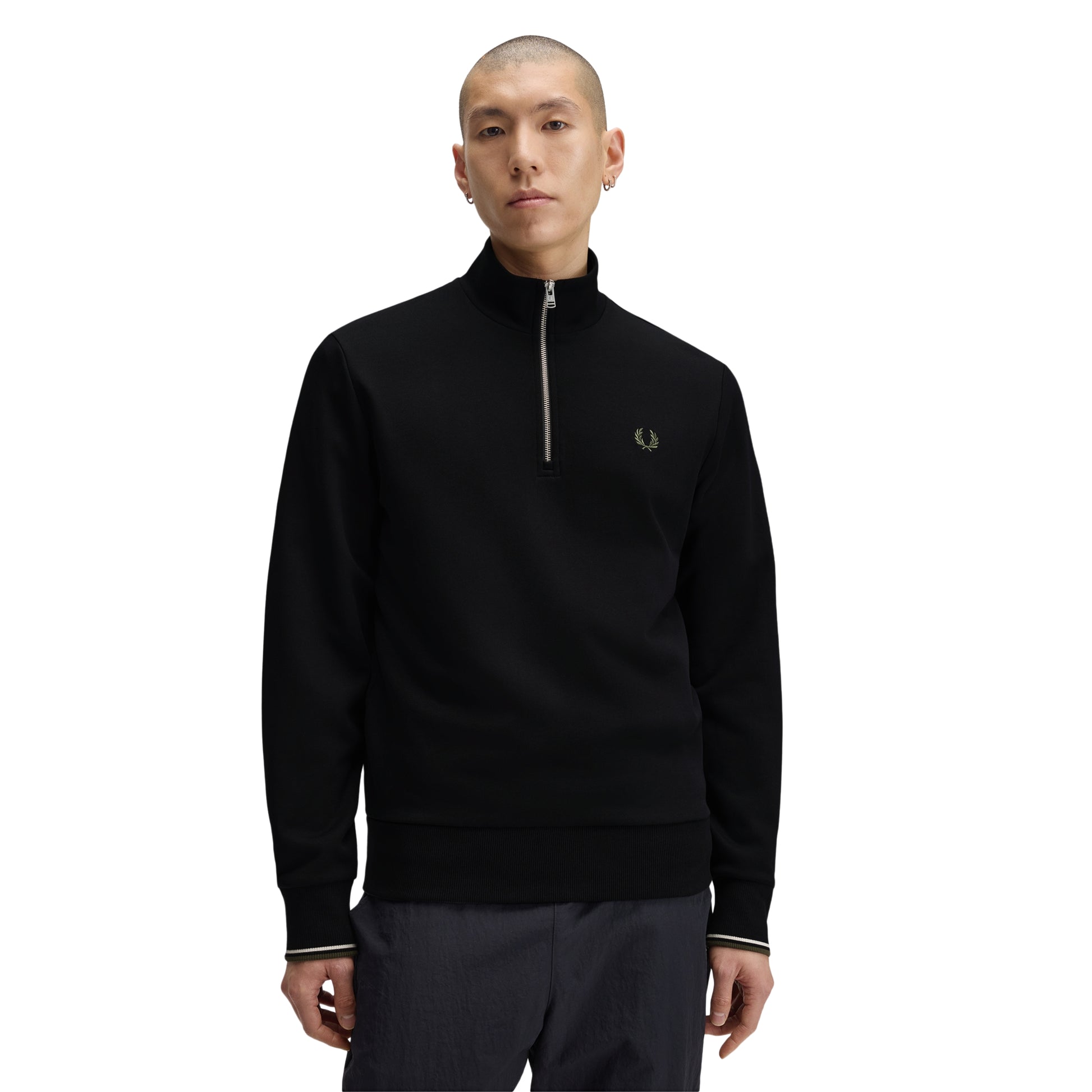 Sweat com meio-fecho Fred Perry Half Zip Sweatshirt em Black — vista frontal com modelo, meio corpo, meio-fecho metálico fechado, bordado Laurel Wreath em Laurel Wreath Green no peito esquerdo, twin tipping Ecru/Laurel Wreath Green nos punhos, combinado com calças navy.