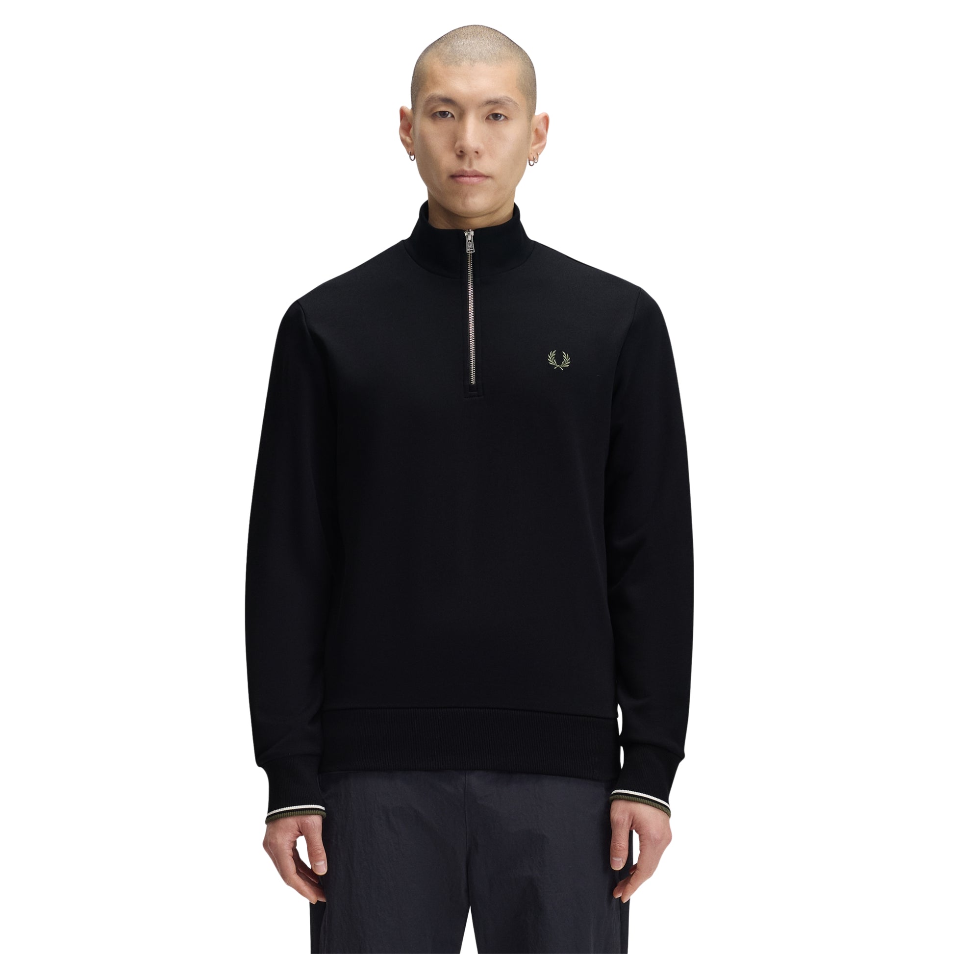 Sweat com meio-fecho Fred Perry Half Zip Sweatshirt em Black — vista frontal com modelo, meio corpo, ângulo ligeiramente diferente, bordado Laurel Wreath em Laurel Wreath Green e twin tipping nos punhos visíveis, combinado com calças navy.