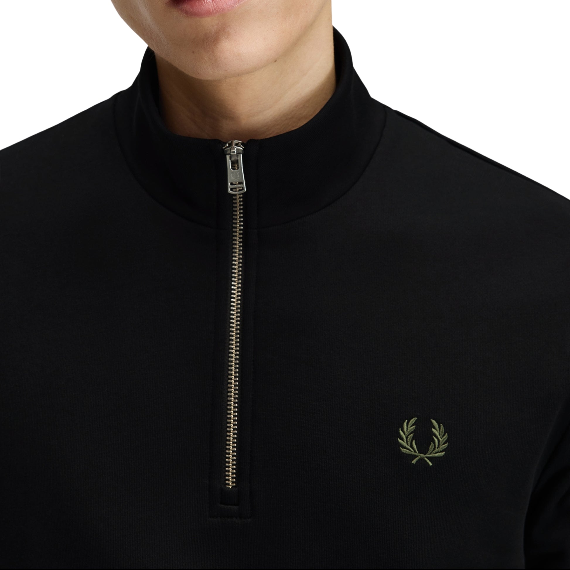Sweat com meio-fecho Fred Perry Half Zip Sweatshirt em Black — vista lateral com modelo, corpo inteiro, perfil do meio-fecho e gola alta visíveis, twin tipping Ecru/Laurel Wreath Green nos punhos, combinado com calças navy.