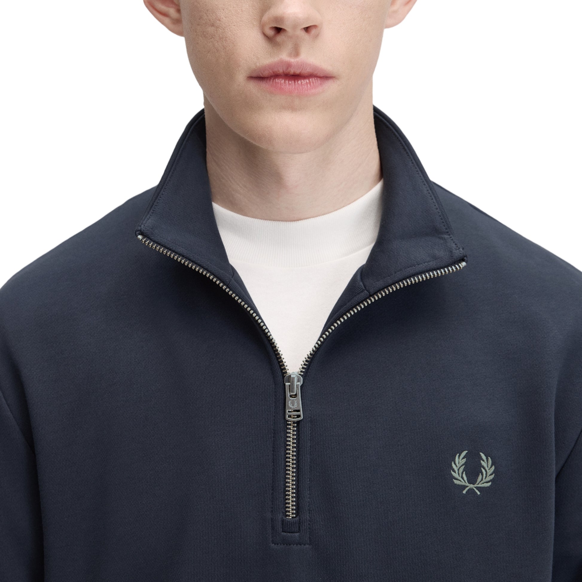 Sweat com meio-fecho Fred Perry Half Zip Sweatshirt em Dark Airforce — detalhe do meio-fecho aberto e bordado Laurel Wreath em Seagrass no peito esquerdo, t-shirt branca por baixo visível.