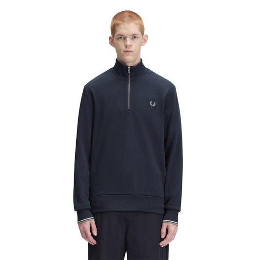 Sweat com meio-fecho Fred Perry Half Zip Sweatshirt em Dark Airforce — vista frontal com modelo, meio corpo, meio-fecho fechado, bordado Laurel Wreath em Seagrass no peito esquerdo, combinado com calças pretas Fred Perry.