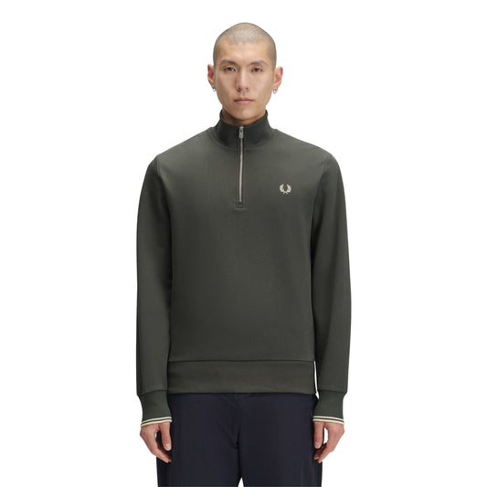 Sweat com meio-fecho Fred Perry Half Zip Sweatshirt em Field Green — vista frontal com modelo, corpo inteiro, meio-fecho fechado, bordado Laurel Wreath em Oatmeal e twin tipping nos punhos visíveis, combinado com calças navy Fred Perry.