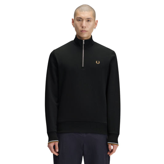 Sweat com meio-fecho Fred Perry Half Zip Sweatshirt em Night Green — vista frontal com modelo, corpo inteiro, meio-fecho fechado, bordado Laurel Wreath em Dark Caramel e twin tipping nos punhos visíveis, combinado com calças navy.