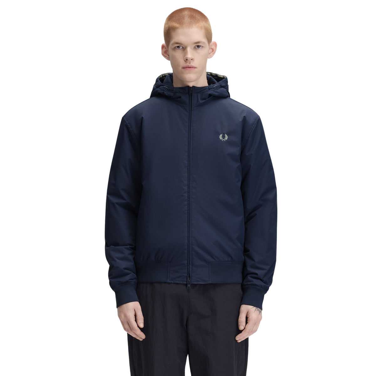 Casaco com carapuço para homem Fred Perry Hooded Brentham Jacket em Dark Airforce — modelo masculino de frente, meio corpo, casaco azul-marinha escuro com capuz ajustável, fecho de correr frontal, logo laurel wreath bordado a bege no peito esquerdo, regular fit, calças pretas, fundo branco.