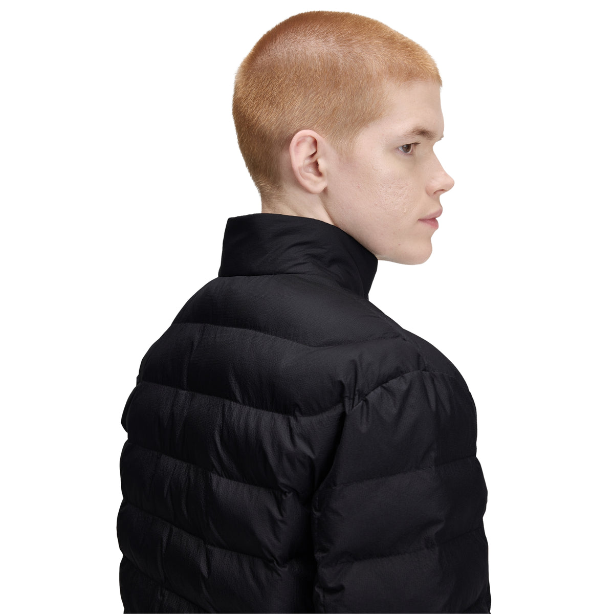 Casaco acolchoado para homem Fred Perry Insulated Jacket em Black — modelo masculino de perfil esquerdo, meio corpo superior, nylon reciclado preto, gola alta com twin tipping interno visível, enchimento acolchoado horizontal nos ombros e tronco, zip central preto, fundo branco.