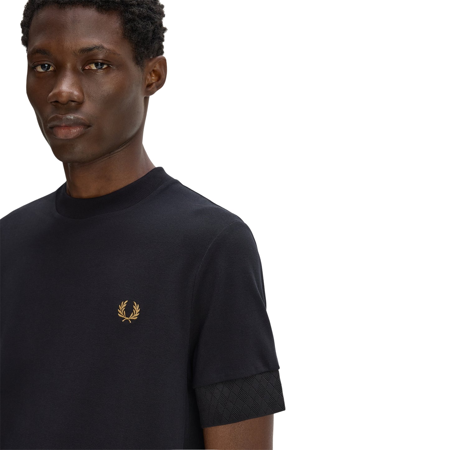 T-shirt Fred Perry Jacquard Cuff T-Shirt em Black — detalhe do punho com acabamento jacquard tonal e bordado Laurel Wreath no peito esquerdo, close-up com modelo.