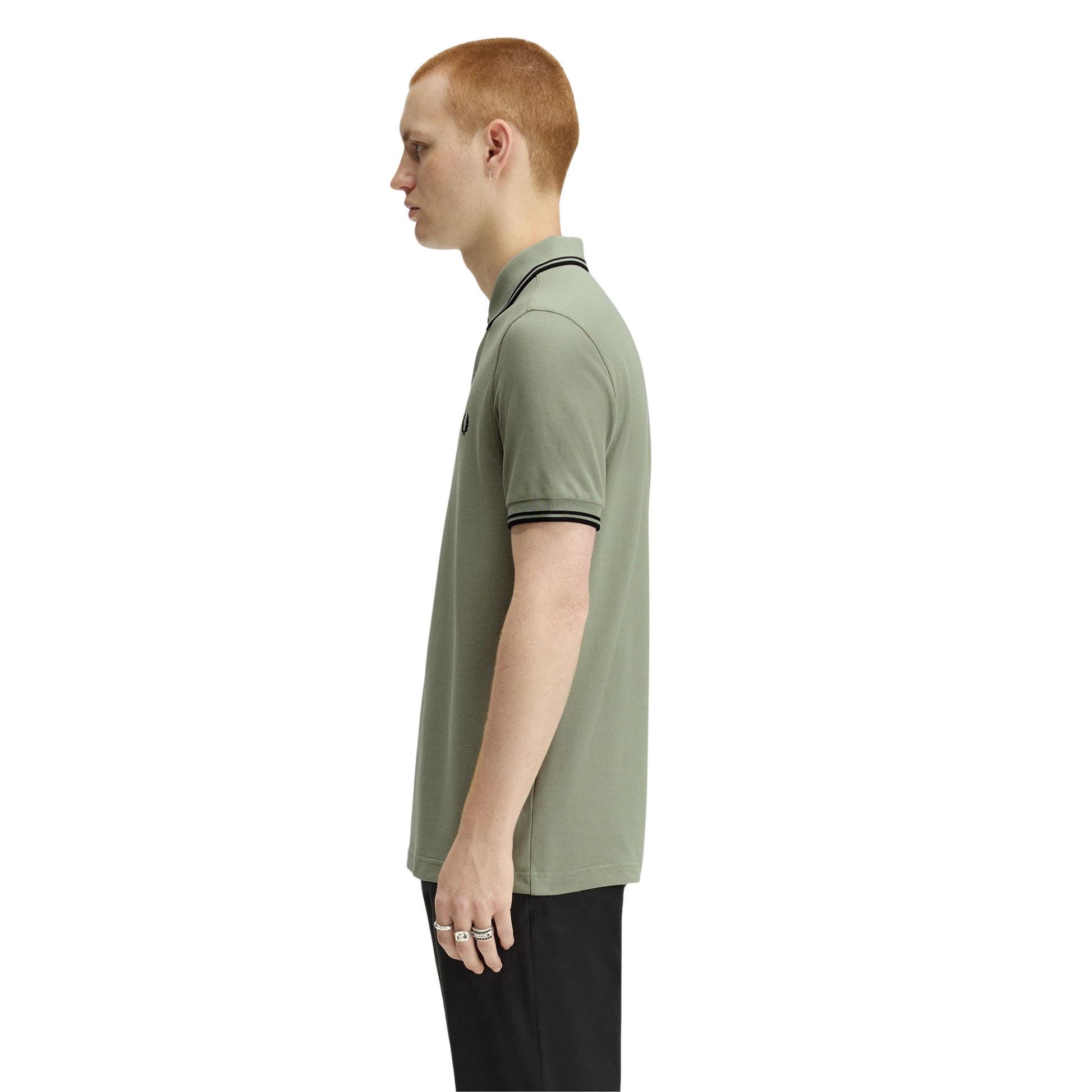 Polo de manga curta para homem Fred Perry M3600 em Seagrass/Preto/Preto. Foto da lateral, vestido.