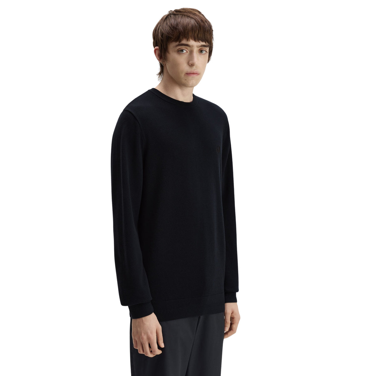 Camisola de malha para homem Fred Perry Pique Stitch Jumper em Navy — modelo masculino de três quartos direito, corpo inteiro, malha piqué azul-marinha escura, gola redonda canelada, barra canelada visível, regular fit, calças escuras, fundo branco.
