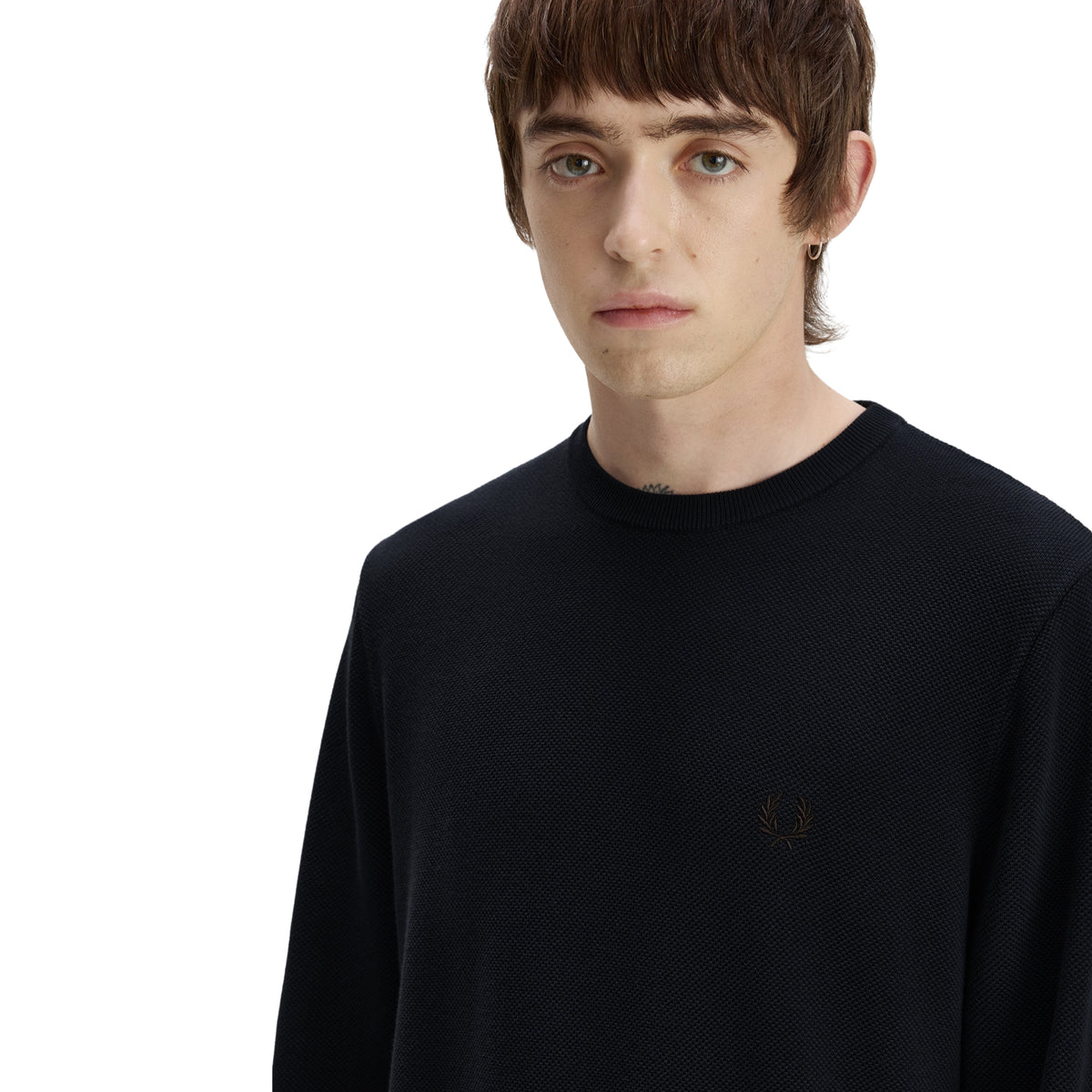Camisola de malha para homem Fred Perry Pique Stitch Jumper em Navy — modelo masculino de frente, meio corpo, malha piqué azul-marinha escura, logo laurel wreath bordado em tom sobre tom no peito esquerdo claramente visível, textura piqué do algodão visível, gola redonda canelada, fundo branco.