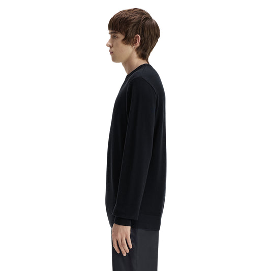 Camisola de malha para homem Fred Perry Pique Stitch Jumper em Navy — modelo masculino de perfil esquerdo, corpo inteiro, malha piqué azul-marinha escura, gola redonda canelada, punho canelado visível, barra canelada, regular fit, calças escuras, fundo branco.