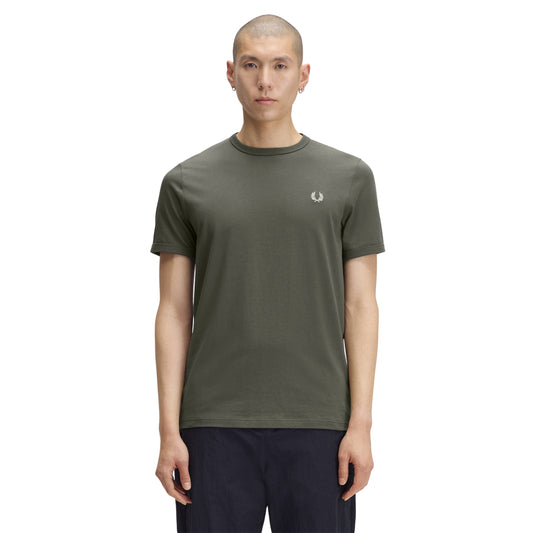 T-shirt de manga curta para homem Fred Perry Ringer T-Shirt em Field Green — modelo masculino de frente, corpo inteiro, jersey verde-musgo Field Green, gola redonda canelada em contraste escuro, logo laurel wreath bordado a creme no peito esquerdo, regular fit, calças azul-marinho, fundo branco.