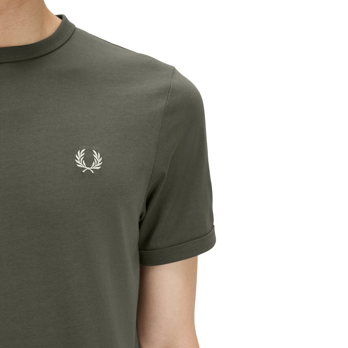 T-shirt de manga curta para homem Fred Perry Ringer T-Shirt em Field Green — detalhe do peito esquerdo e ombro direito, jersey verde-musgo Field Green, logo laurel wreath bordado a creme em close-up bem visível, punho canelado em contraste escuro visível, gola canelada em contraste parcialmente visível, fundo branco.