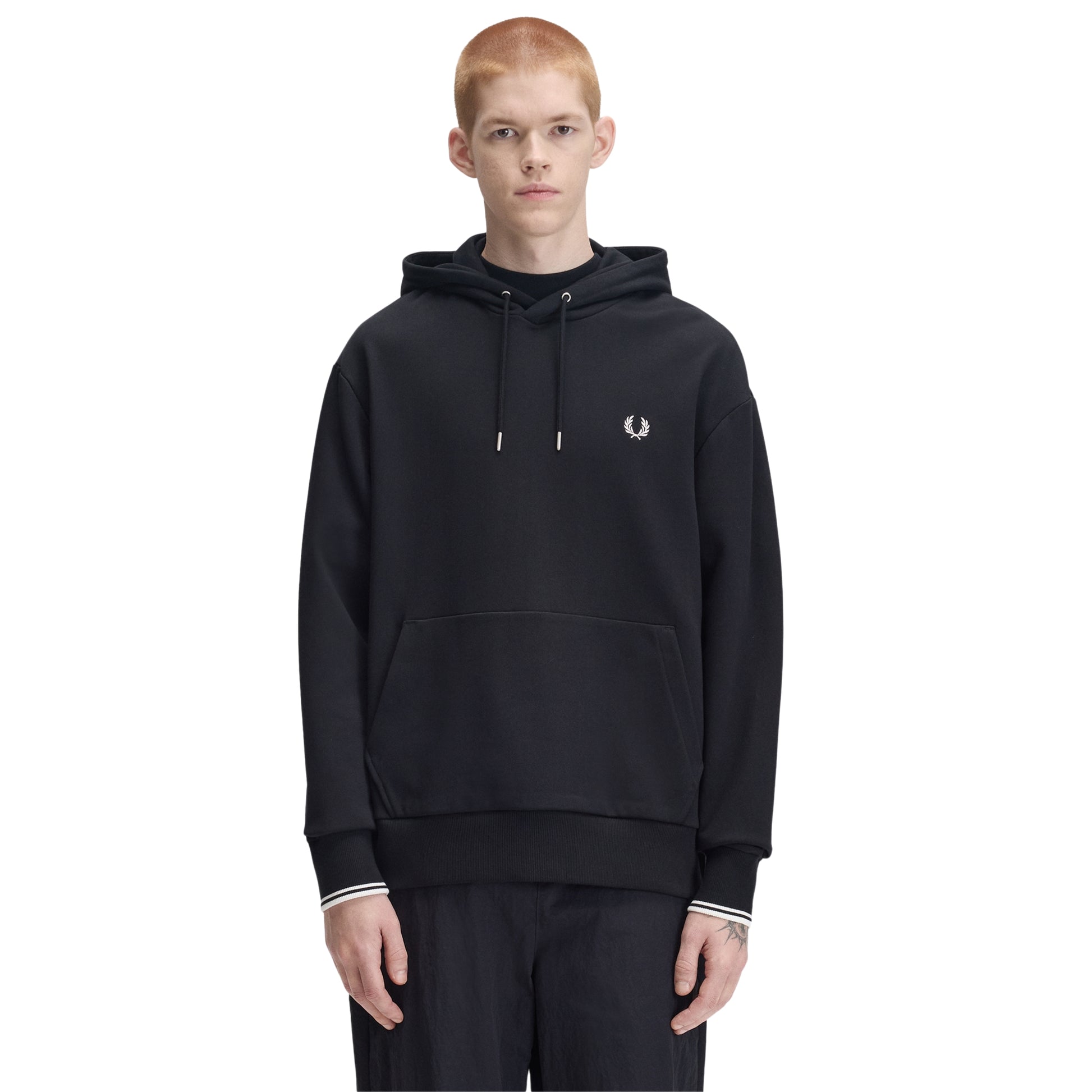 Sweat com carapuço Fred Perry Tipped Hooded Sweatshirt em Black — vista frontal com modelo, meio corpo, capota com cordões, bordado Laurel Wreath no peito esquerdo, twin tipping nos punhos visível.

