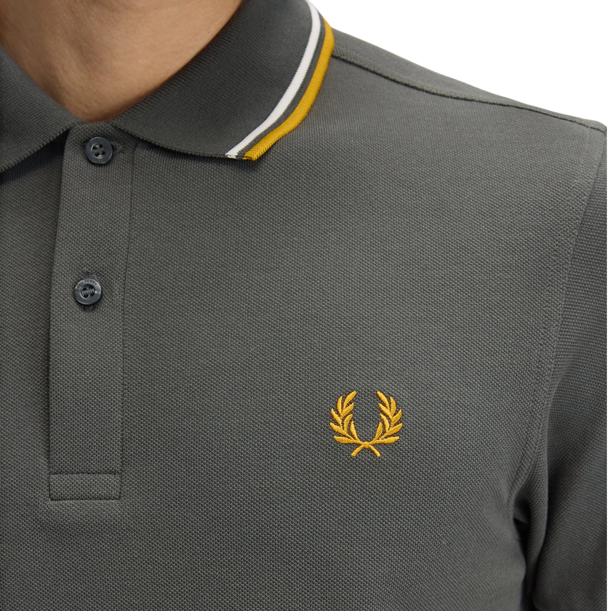 Polo de manga curta para homem Fred Perry Twin Tipped em Field Green/Ecru/Golden. Foto de detalhe da parte da frente, vestido.