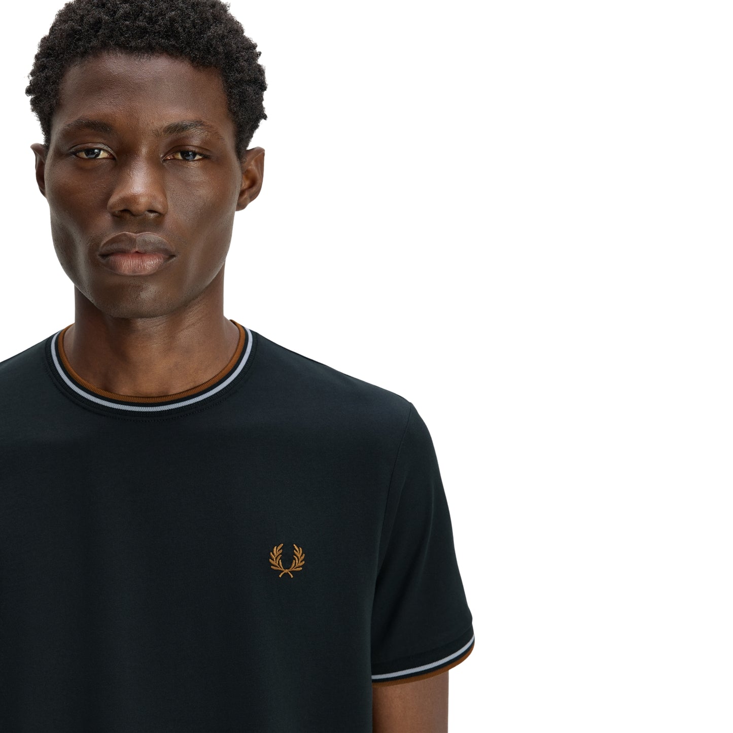 T-shirt Fred Perry Twin Tipped T-Shirt em Night Green — vista de três quartos com modelo, corpo inteiro, bordado Laurel Wreath em Dark Caramel no peito esquerdo e twin tipping no colarinho e punhos visíveis.