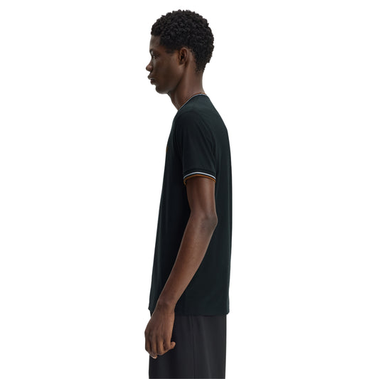 T-shirt Fred Perry Twin Tipped T-Shirt em Night Green — vista frontal com modelo, corpo inteiro, bordado Laurel Wreath em Dark Caramel e twin tipping no colarinho e punhos visíveis.