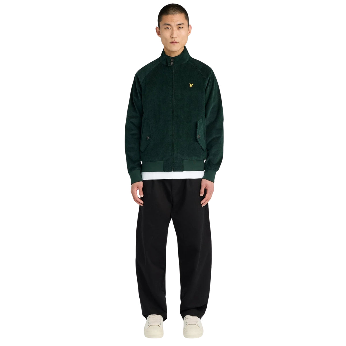 Modelo de corpo inteiro com casaco Lyle & Scott Corduroy Harrington Darkest Green, calças pretas e sapatilhas claras.