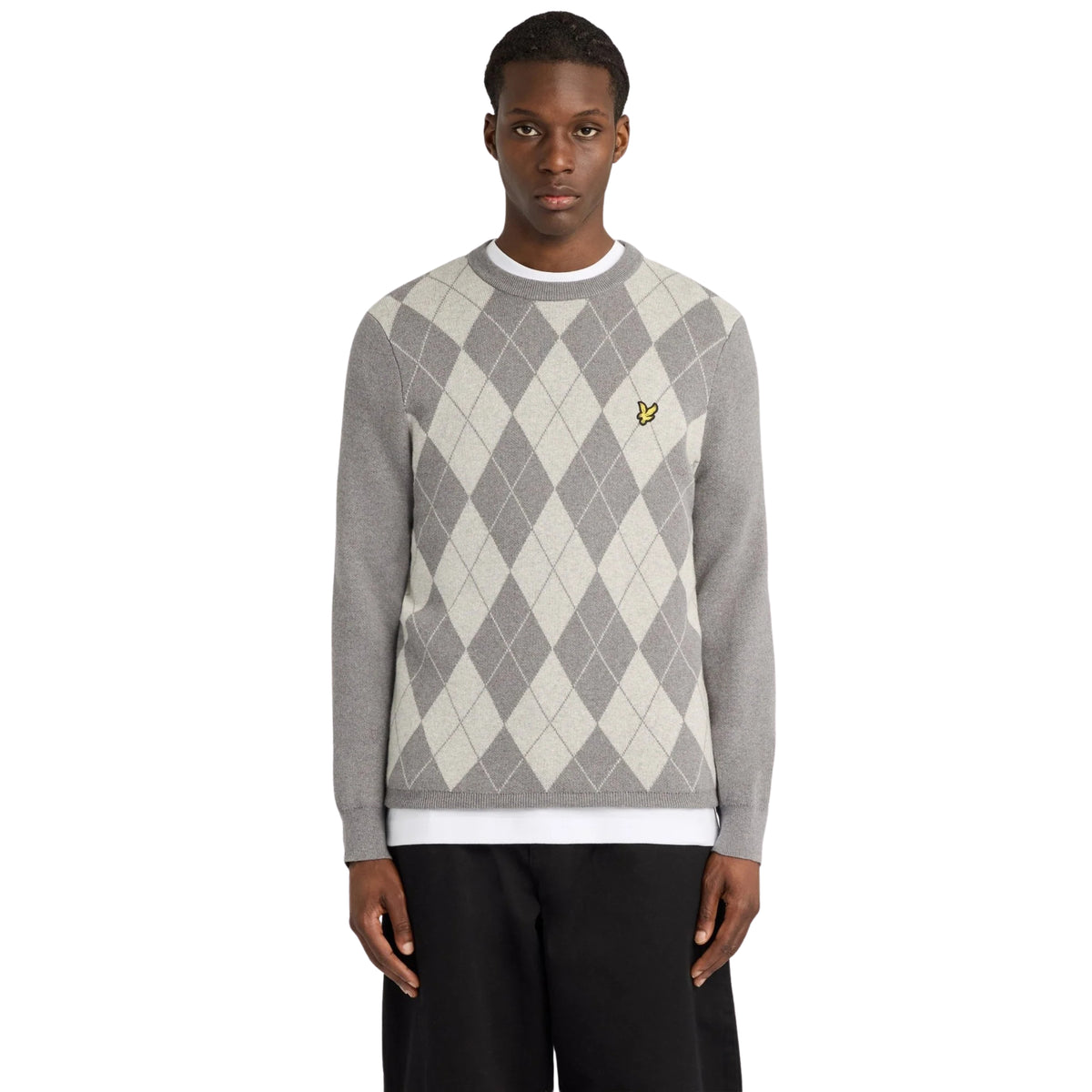 Camisola Lyle & Scott Cotton Merino Argyle em cinzentos mesclados, vestida por modelo de frente, com losangos e águia amarela no peito.