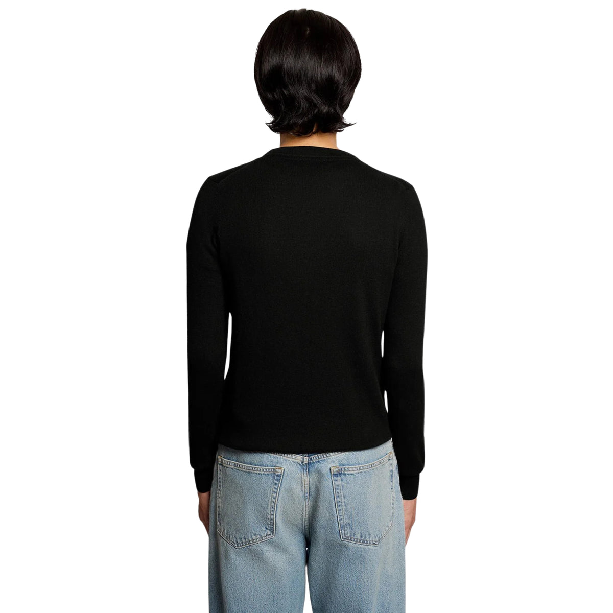 Vista de costas da camisola Lyle & Scott Cotton Merino preta, vestida por modelo com calças de ganga claras.