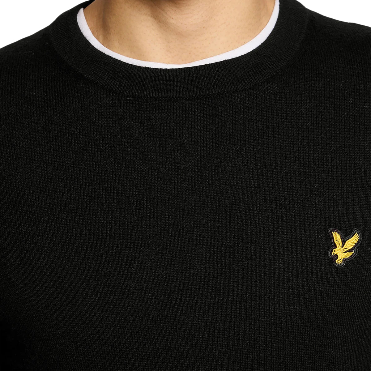 Pormenor da gola redonda canelada e do logótipo no peito da camisola Lyle & Scott Cotton Merino preta.
