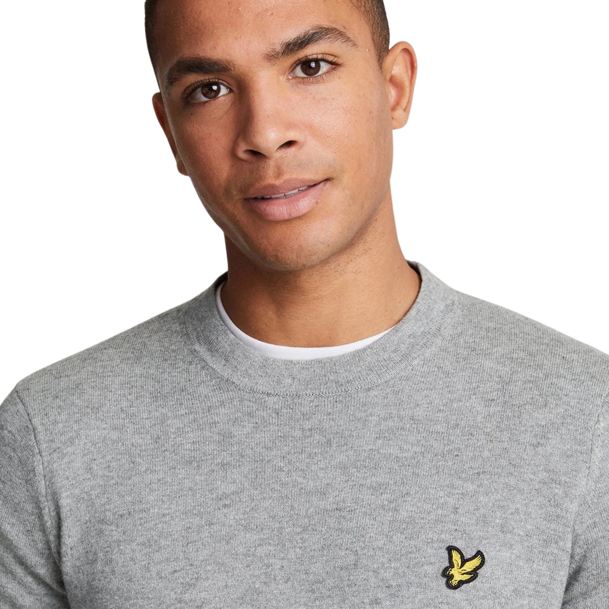Pormenor da gola redonda, malha cinzenta mesclada e águia amarela no peito da camisola Lyle & Scott Cotton Merino.
