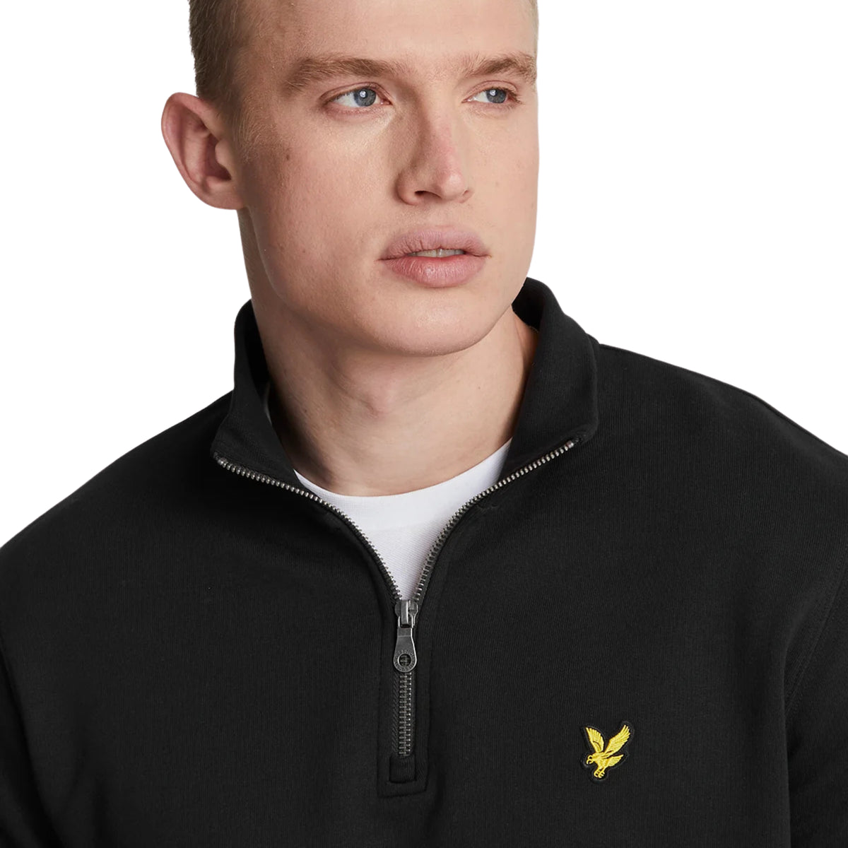 Pormenor da gola com fecho parcialmente aberto e da águia amarela no peito da sweat Lyle & Scott Loopback Jet Black.