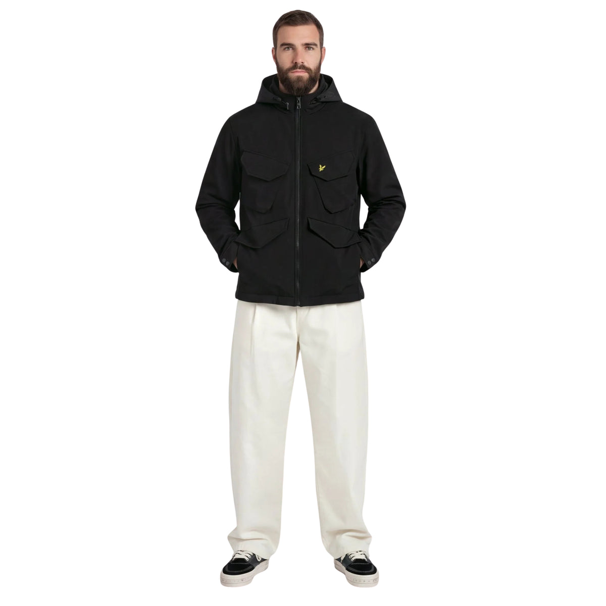 Modelo de corpo inteiro com casaco Lyle & Scott Softshell Field Jet Black, mãos nos bolsos, calças claras e sapatilhas pretas.