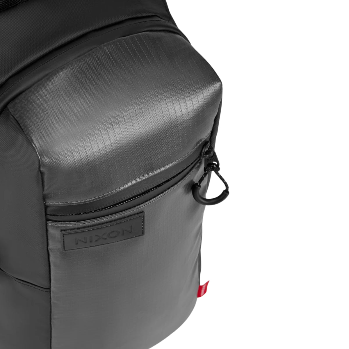 Pormenor do painel frontal da bolsa Nixon Syndicate Sling Bag Asphalt, com textura do tecido, fecho horizontal e logótipo discreto Nixon.